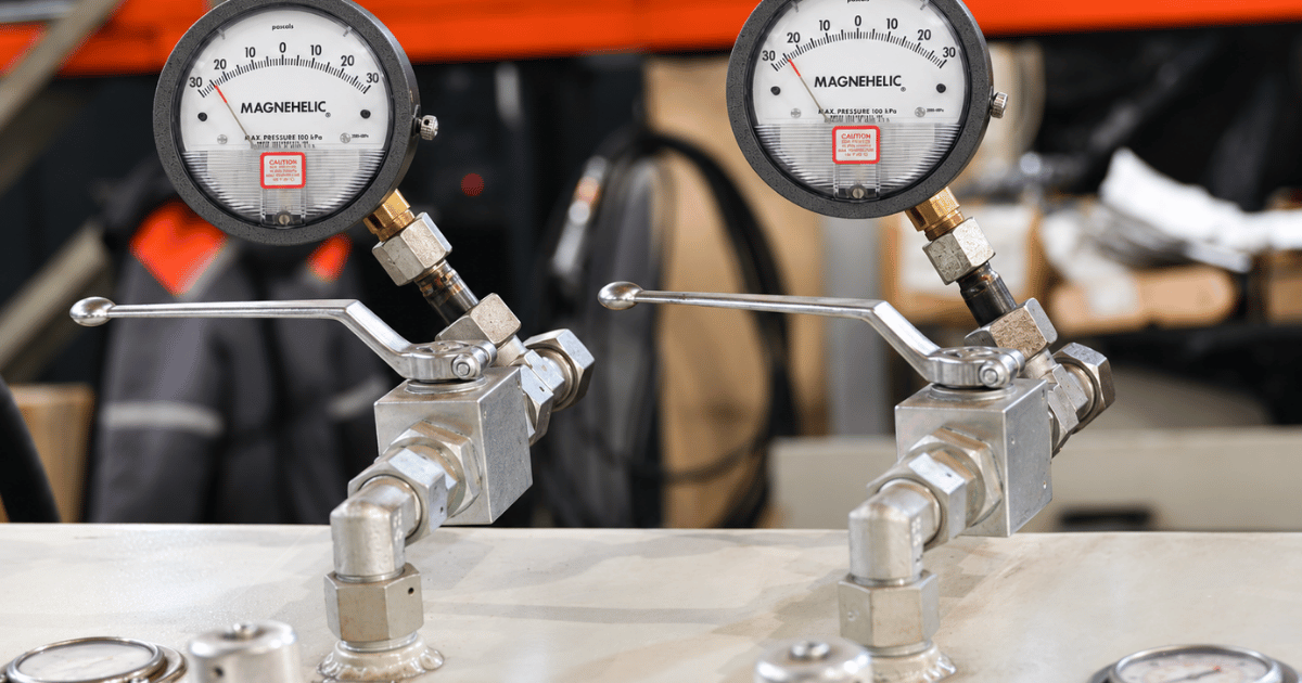 Dwyer Magnehelic differential pressure gauges with ball valve manifolds mounted on workbench in HVAC workshop